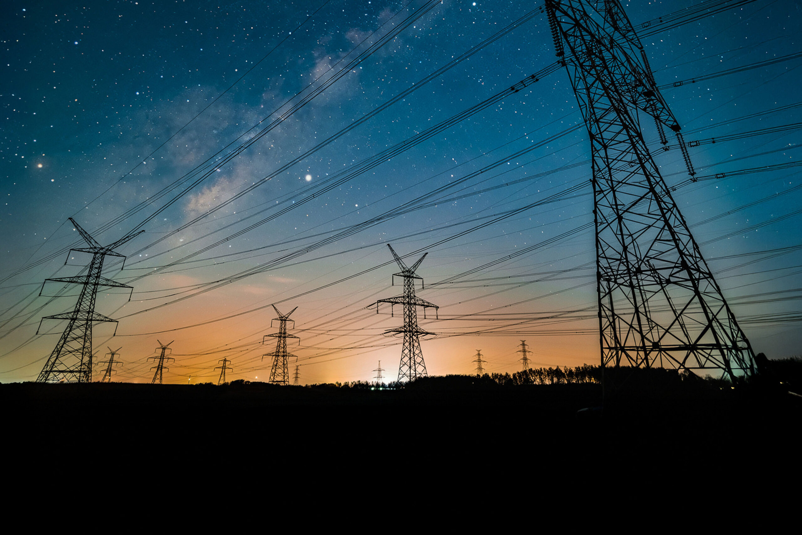 Overhead transmission lines against starry night sky